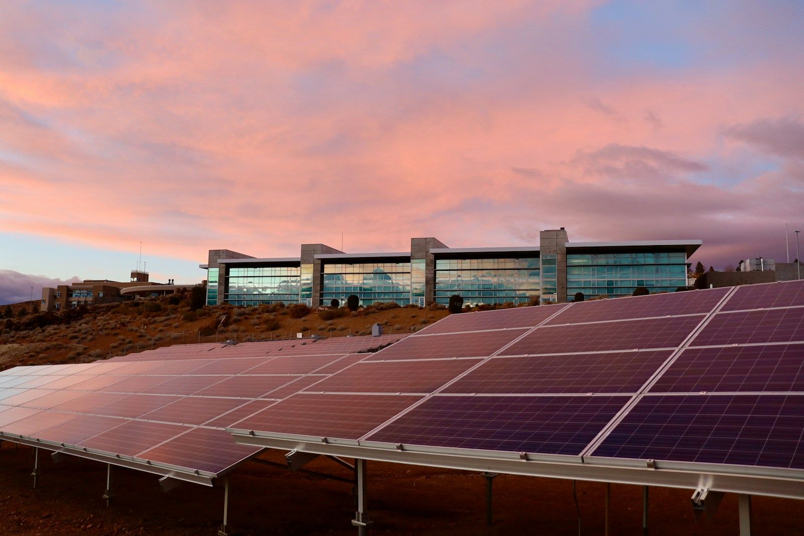 Fotovoltaické panely před firemní budovou při západu slunce